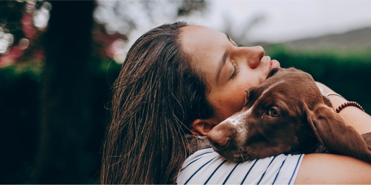 Person cuddling a brown dog.